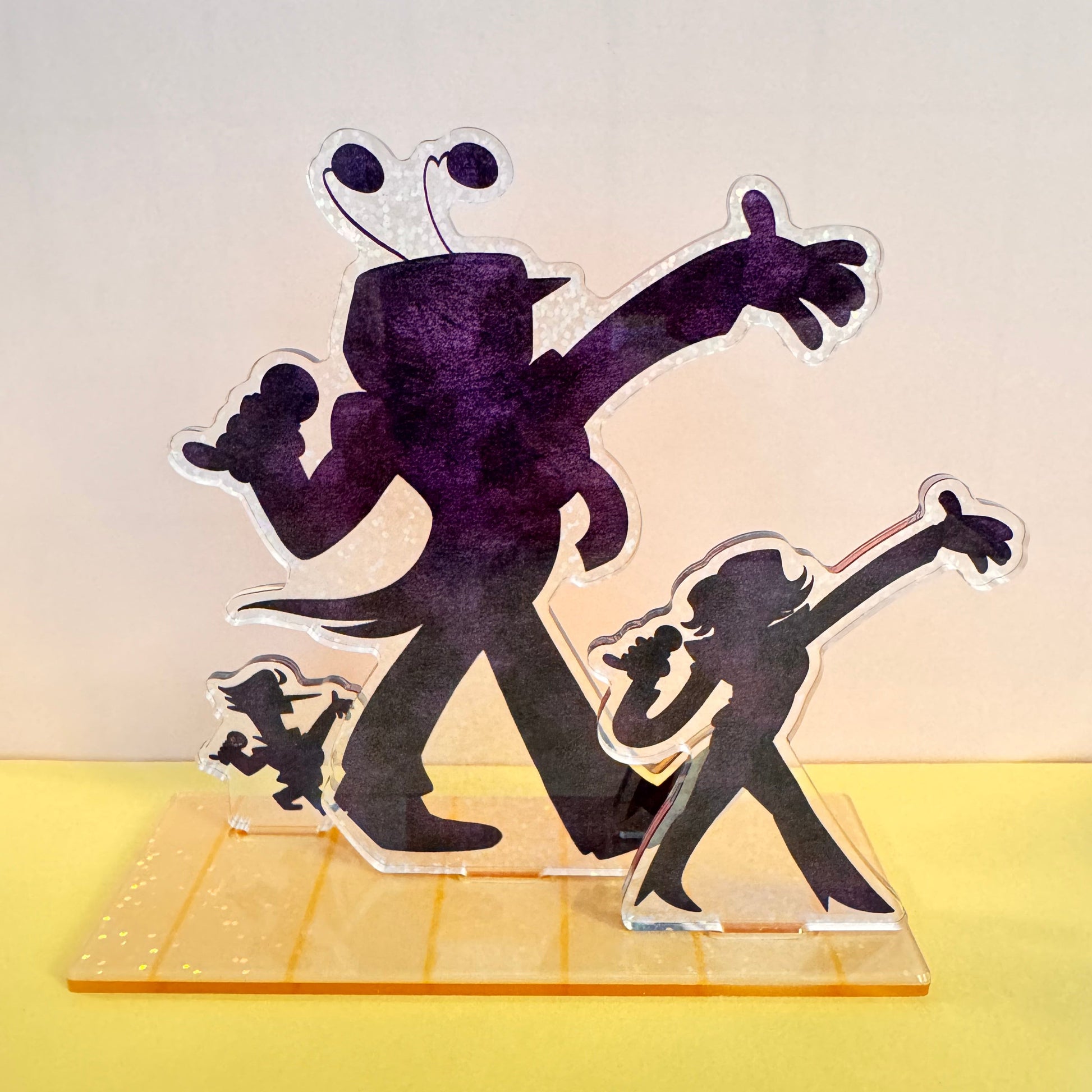 Colorful acrylic cutout of three character silhouettes, Mettaton, Mr. Ant Tenna, and Spamton G. Spamton, with a dynamic pose on a stand.